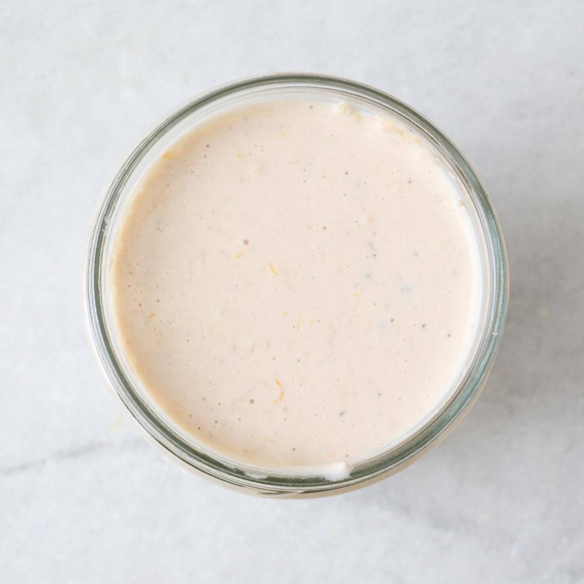 Creamy Caesar salad dressing in a glass jar.