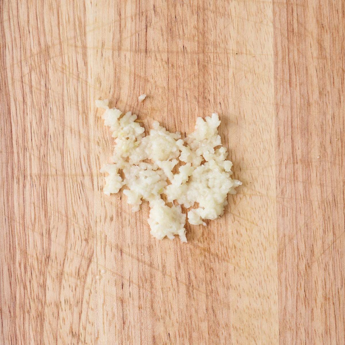Minced garlic on a wooden cutting board.