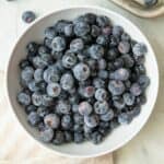Small white bowl of frozen blueberries.