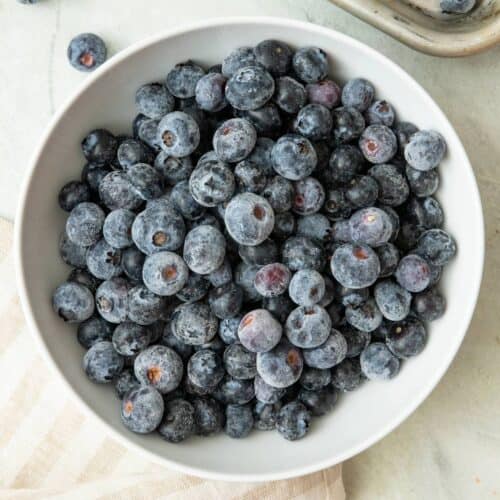 Small white bowl of frozen blueberries.