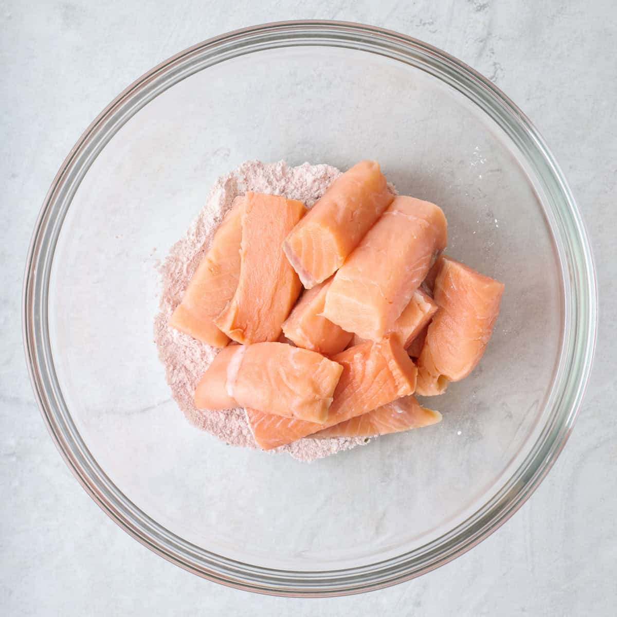 Raw salmon sticks on top of flour for dredging.