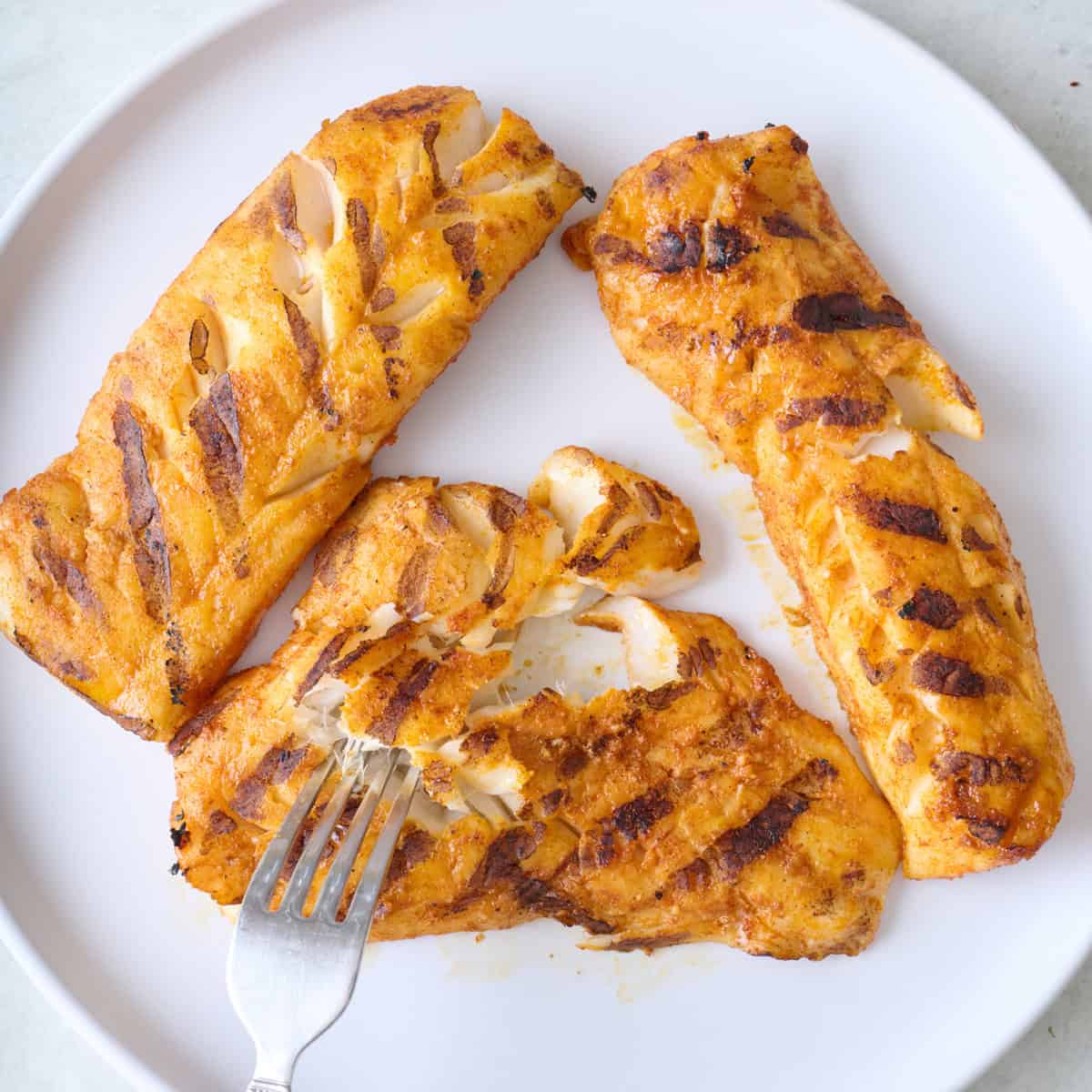 Cooked fish fillets on a plate.