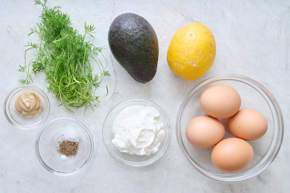 Ingredients for recipe: fresh dill, dijon mustard, salt and pepper, yogurt, avocado, lemon and eggs.