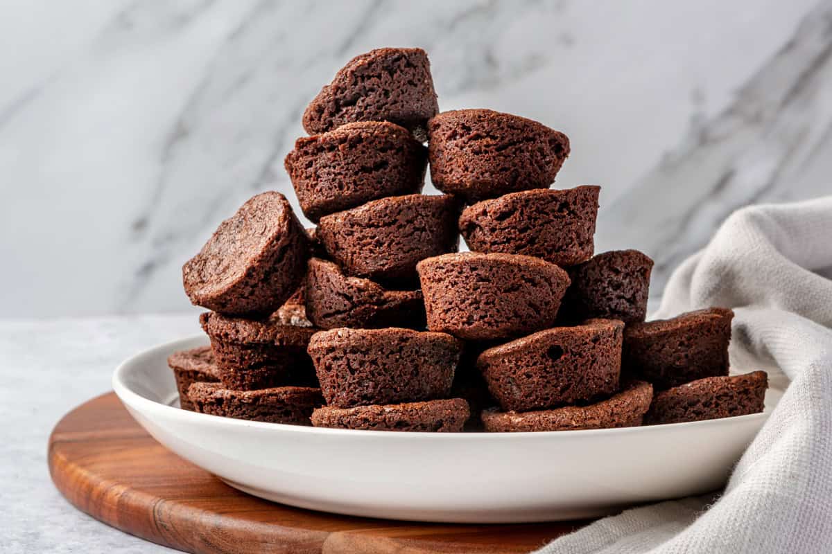 Brownie bites stacked on a white plate. 