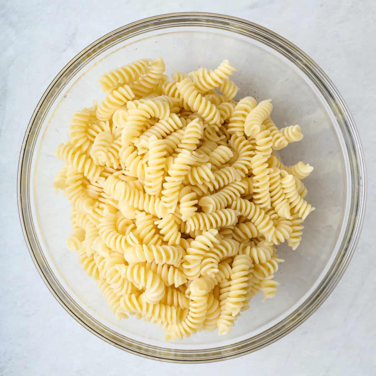 Cooked pasta in a large glass mixing bowl.
