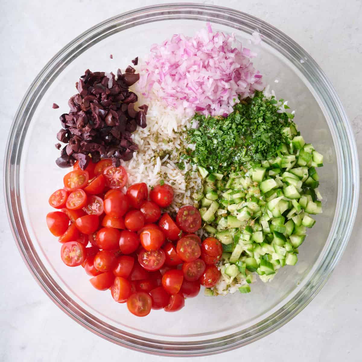 Cooked rice and prepped veggies added on top of dressing.