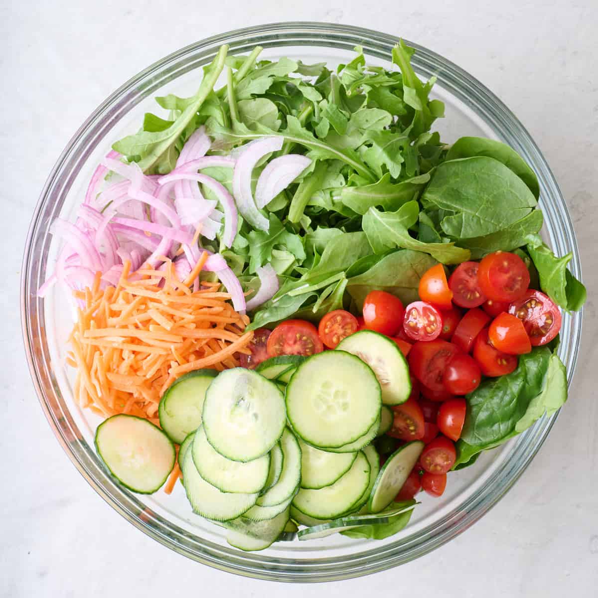 Salad ingredients in a large glass serving bowl.