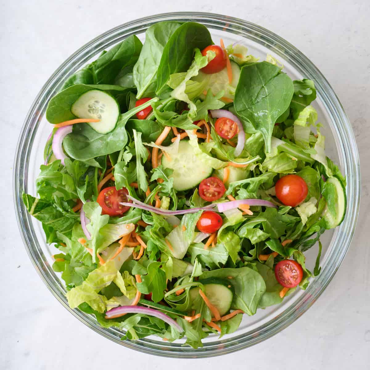 Tossed salad ingredients in a large glass mixing bowl.