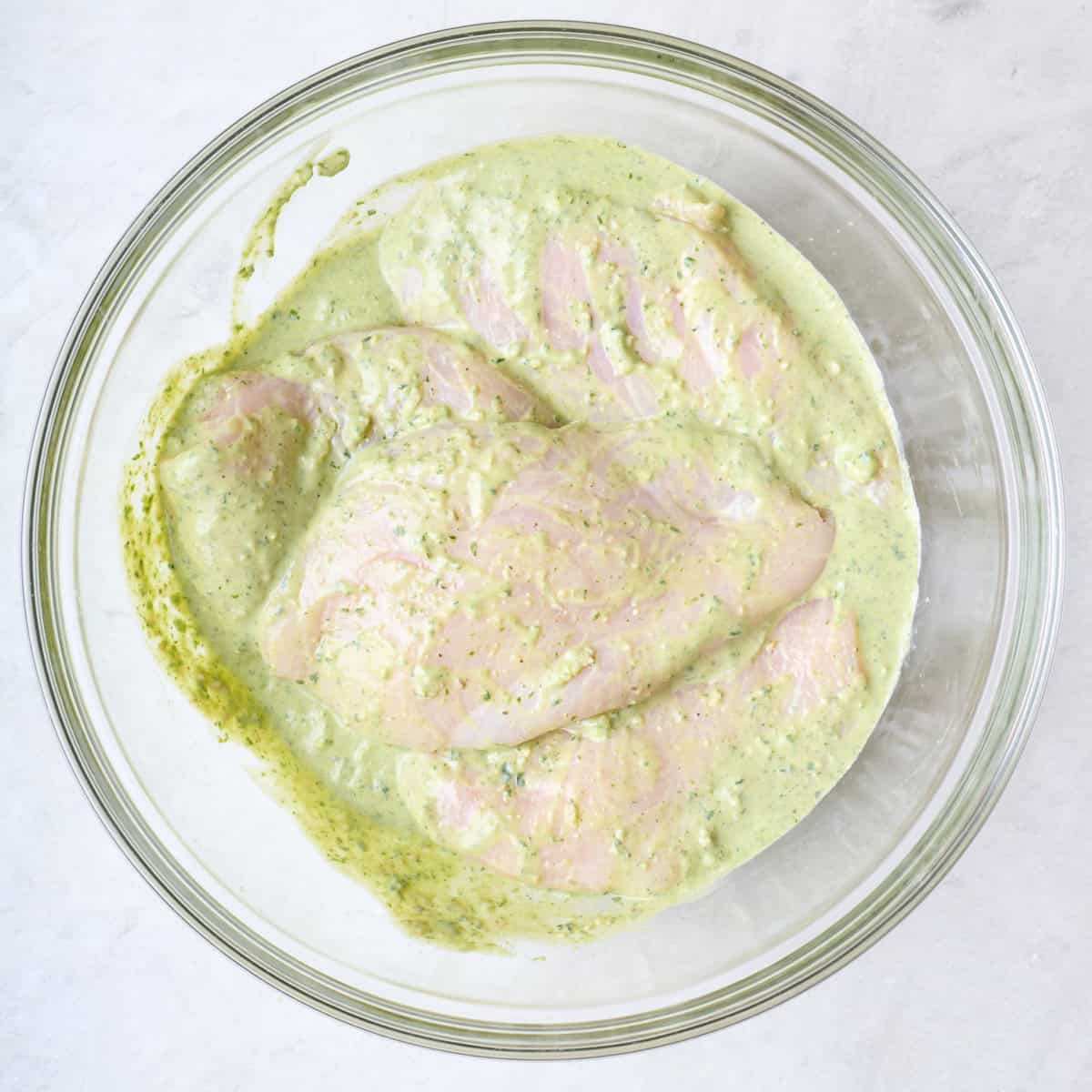 Marinade in bowl after combining with chicken breasts added and coated well.