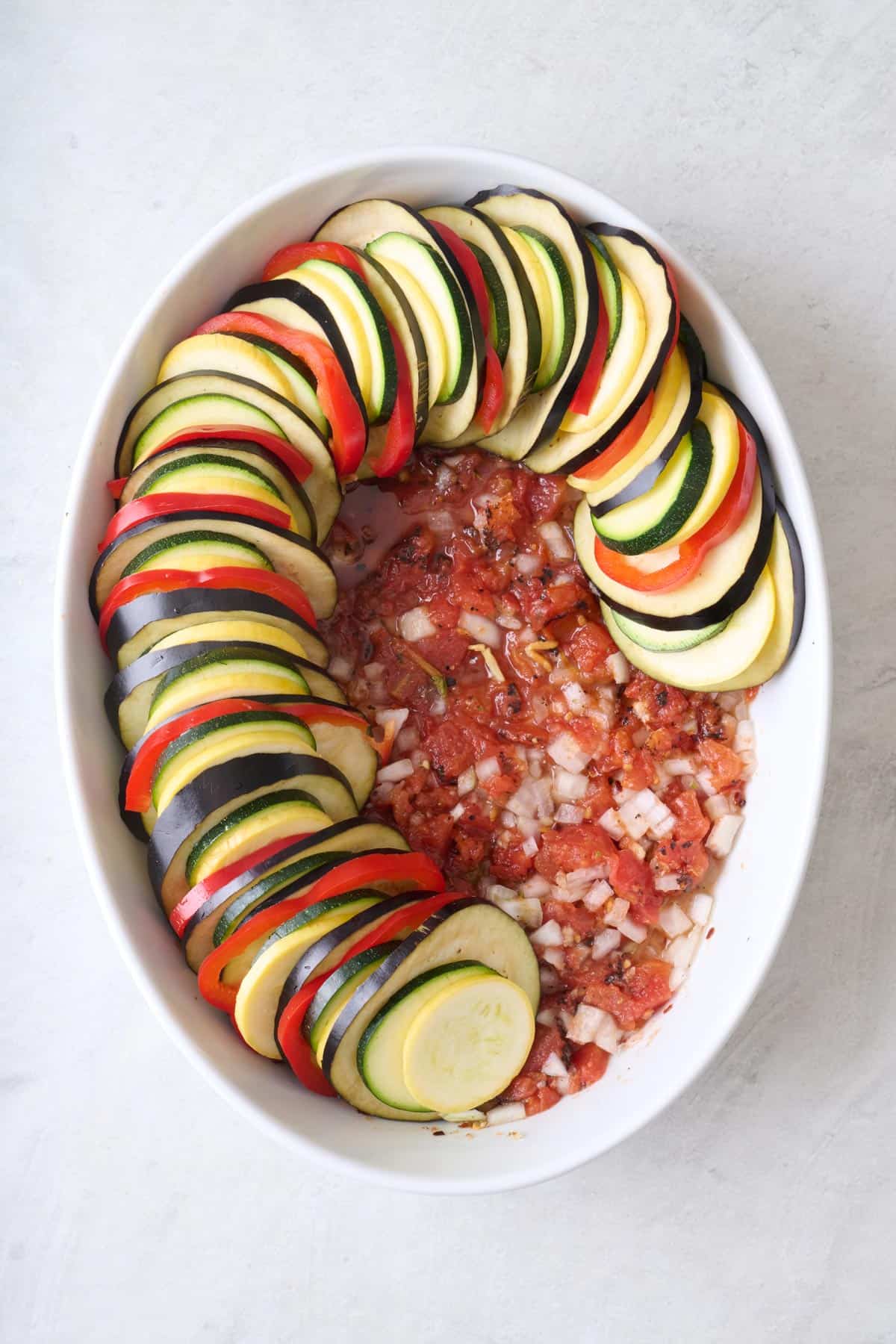After combining with slicings of eggplant, zucchini, squash, and bell pepper alternating around edge of dish, about halfway full.