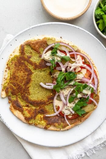 Smash falafel pita with sliced onions, tomatoes, pickles, and tahini sauce.