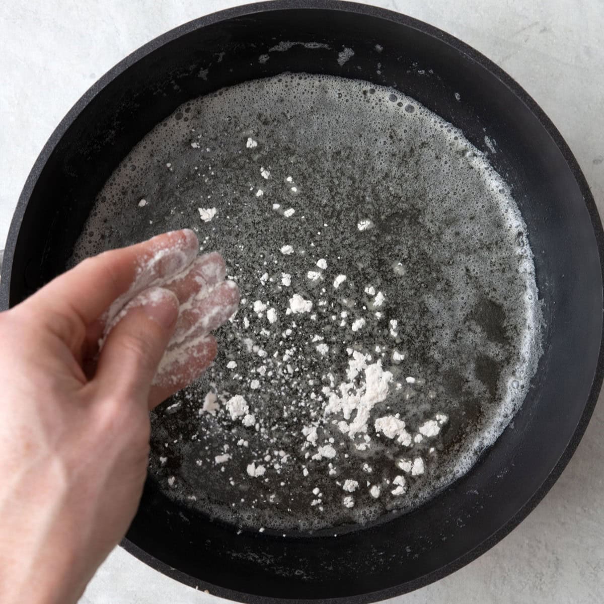 Sprinkling flour over melted butter in a saucepan.