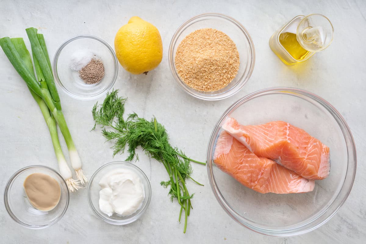 Salmon burger ingredients on a marble kitchen countertop.