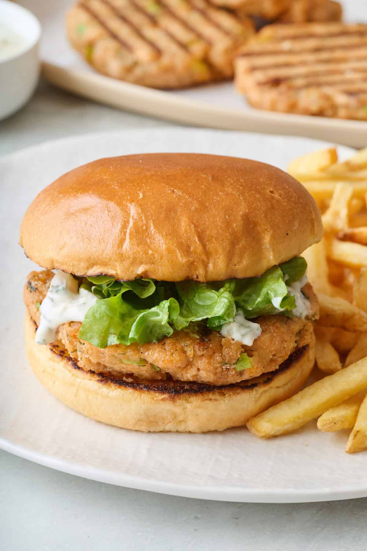 A salmon burger and french fries on a plate.