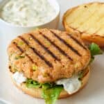 Grilled salmon burger patty on a bun with toppings.