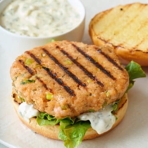 Grilled salmon burger patty on a bun with toppings.