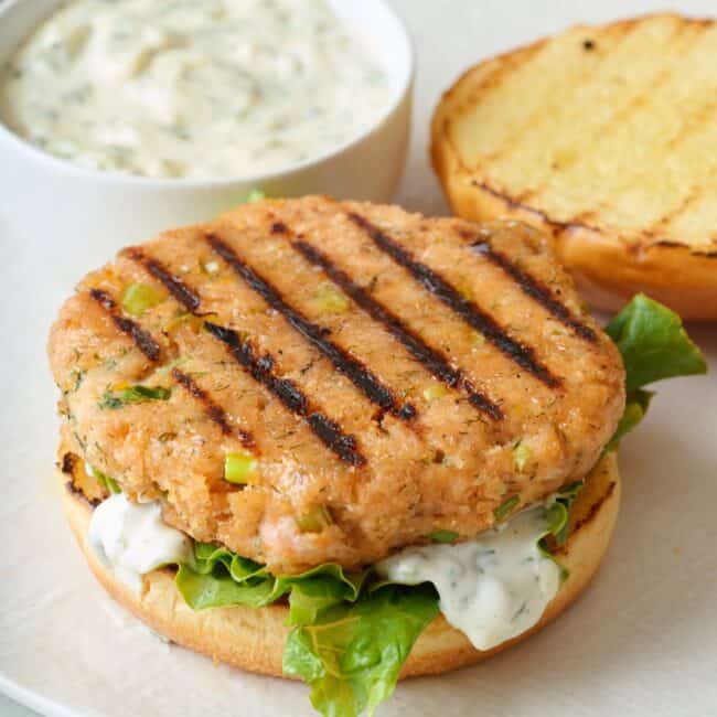 Grilled salmon burger patty on a bun with toppings.