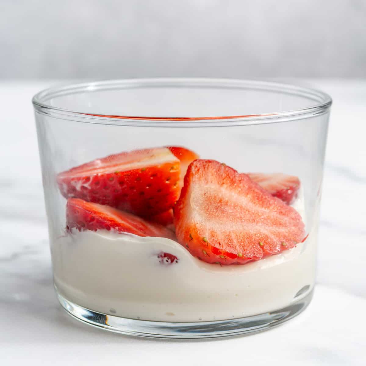 Cream-cheese yogurt mixture and sliced strawberries in a serving glass.