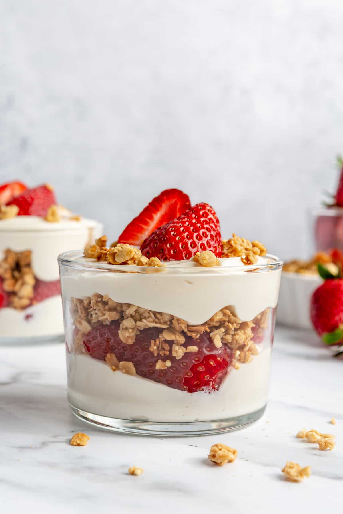 Small cups of strawberry parfait topped with granola and sliced berries.