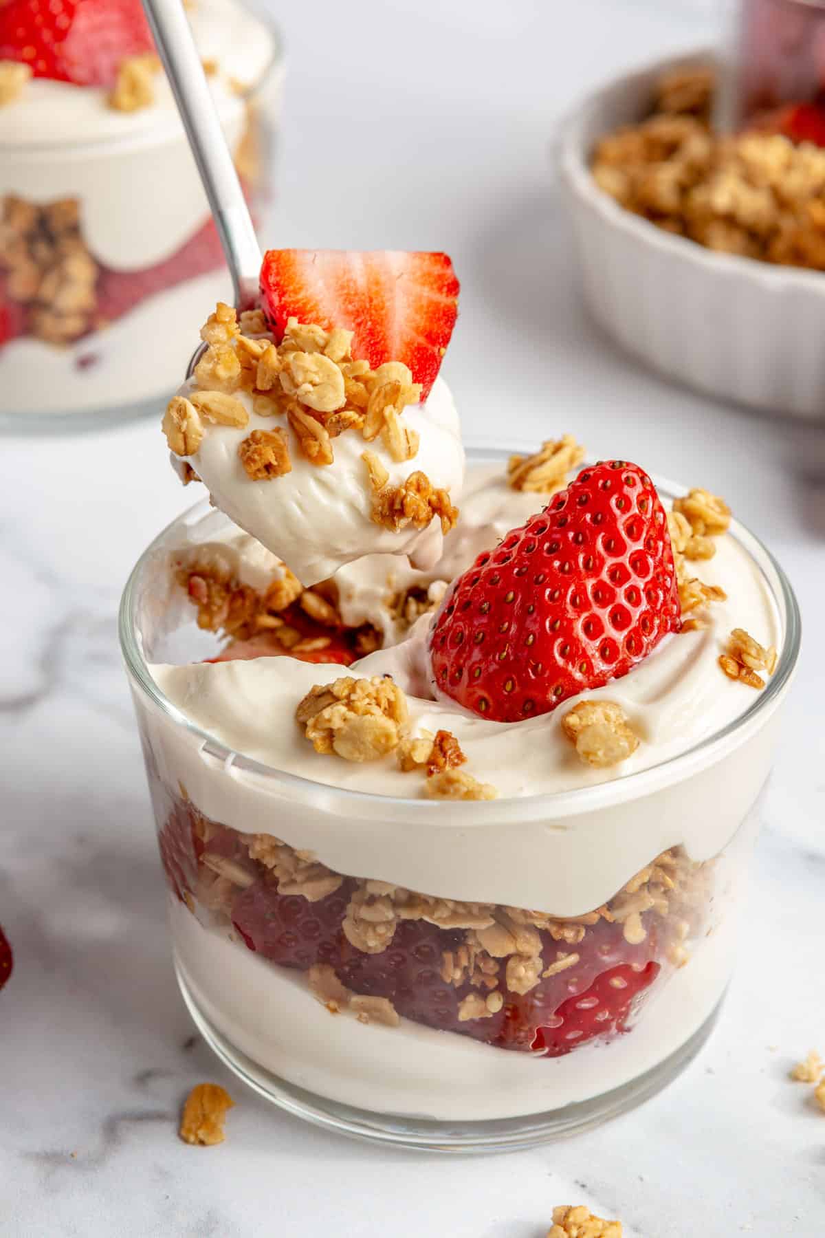 A spoon dipping into a strawberry parfait.