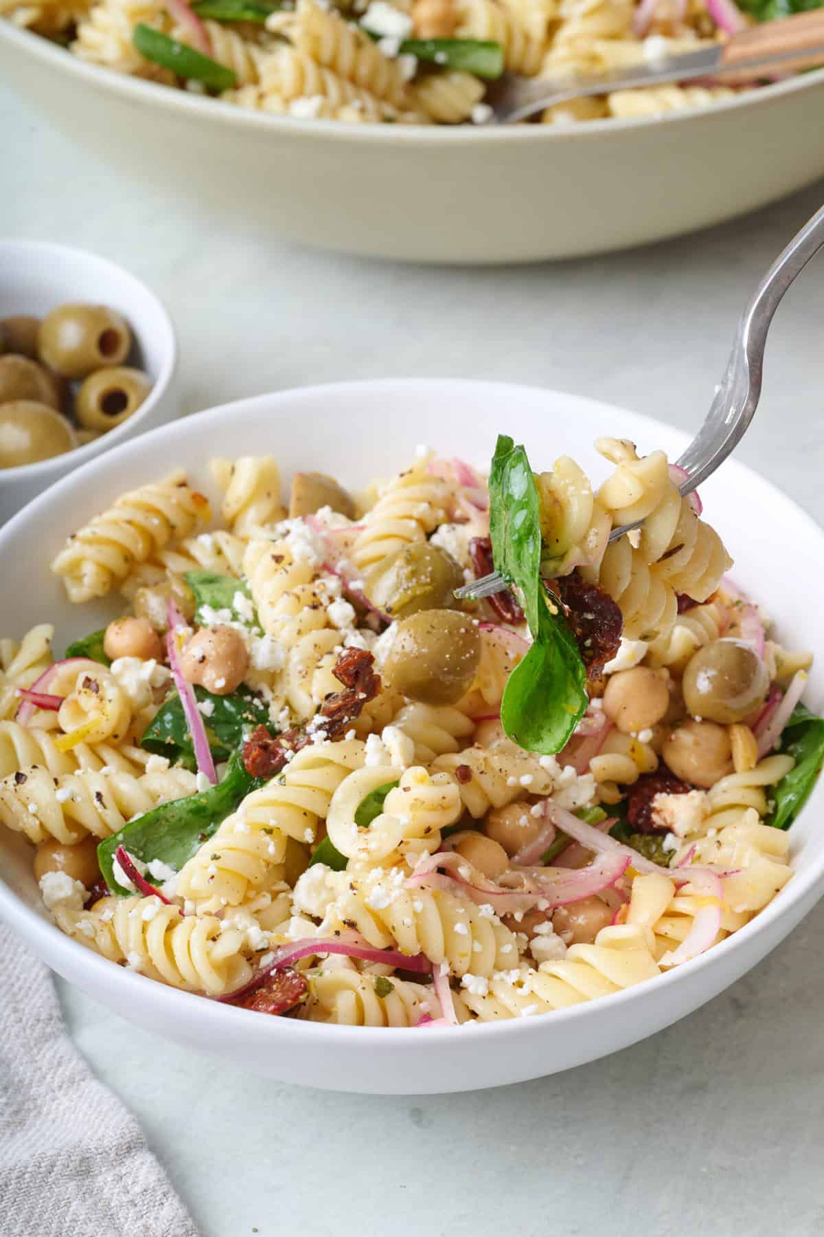 A fork scooping up a bite of sun-dried tomato pasta salad.