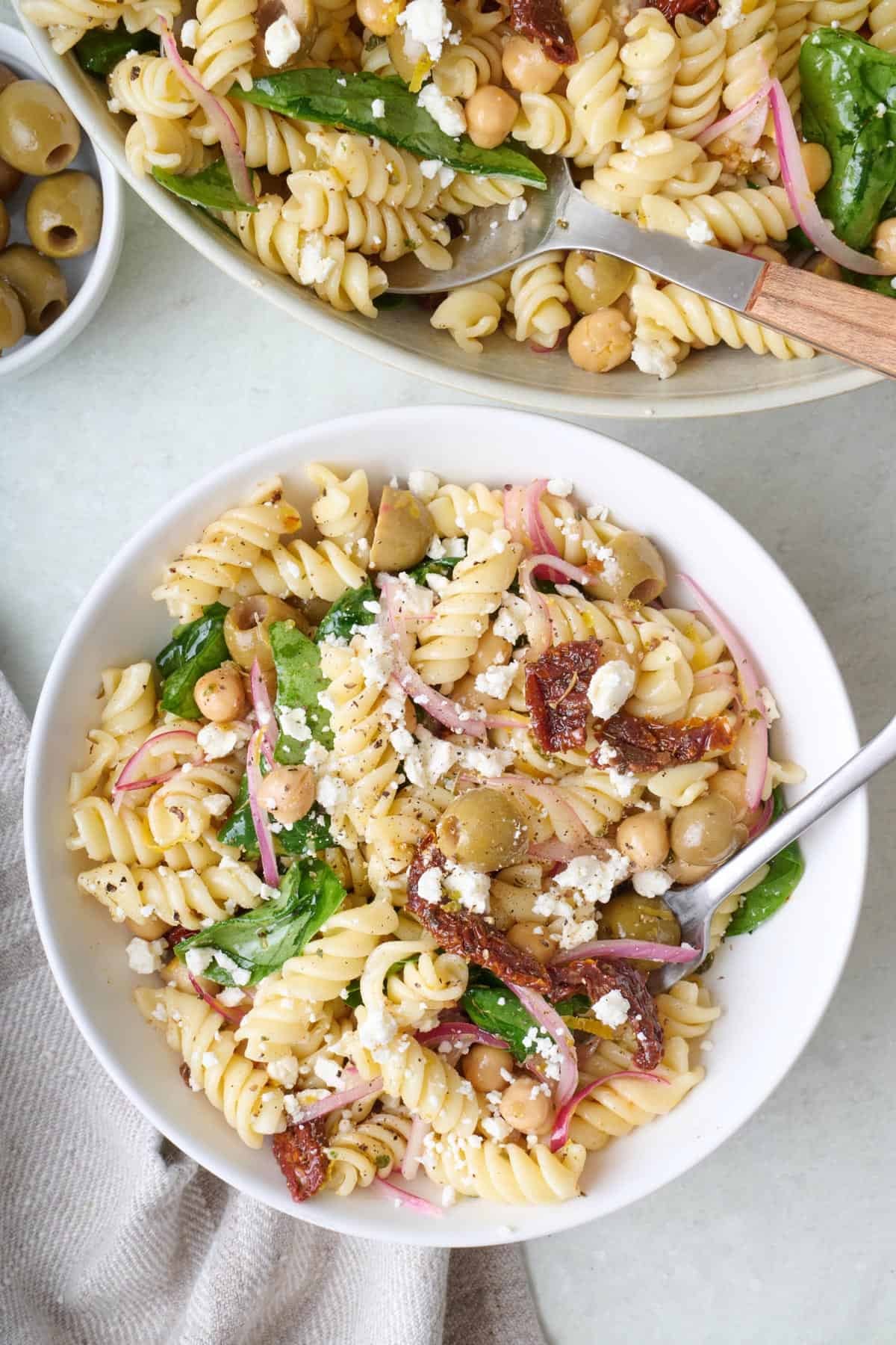 A bowl of sun-dried tomato pasta salad topped with crumbled feta cheese.