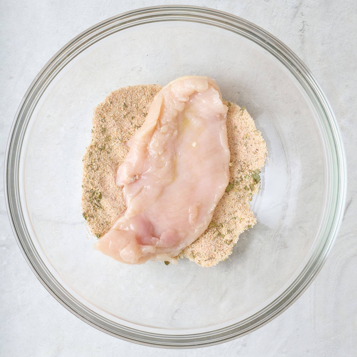Chicken breast on top of breadcrumb mixture.
