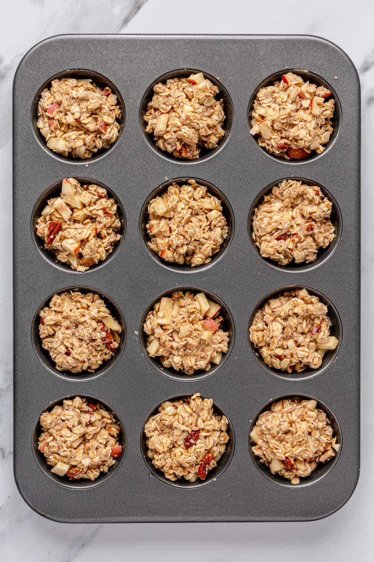Oat mixture added to a 12 cup muffin pan before baking.