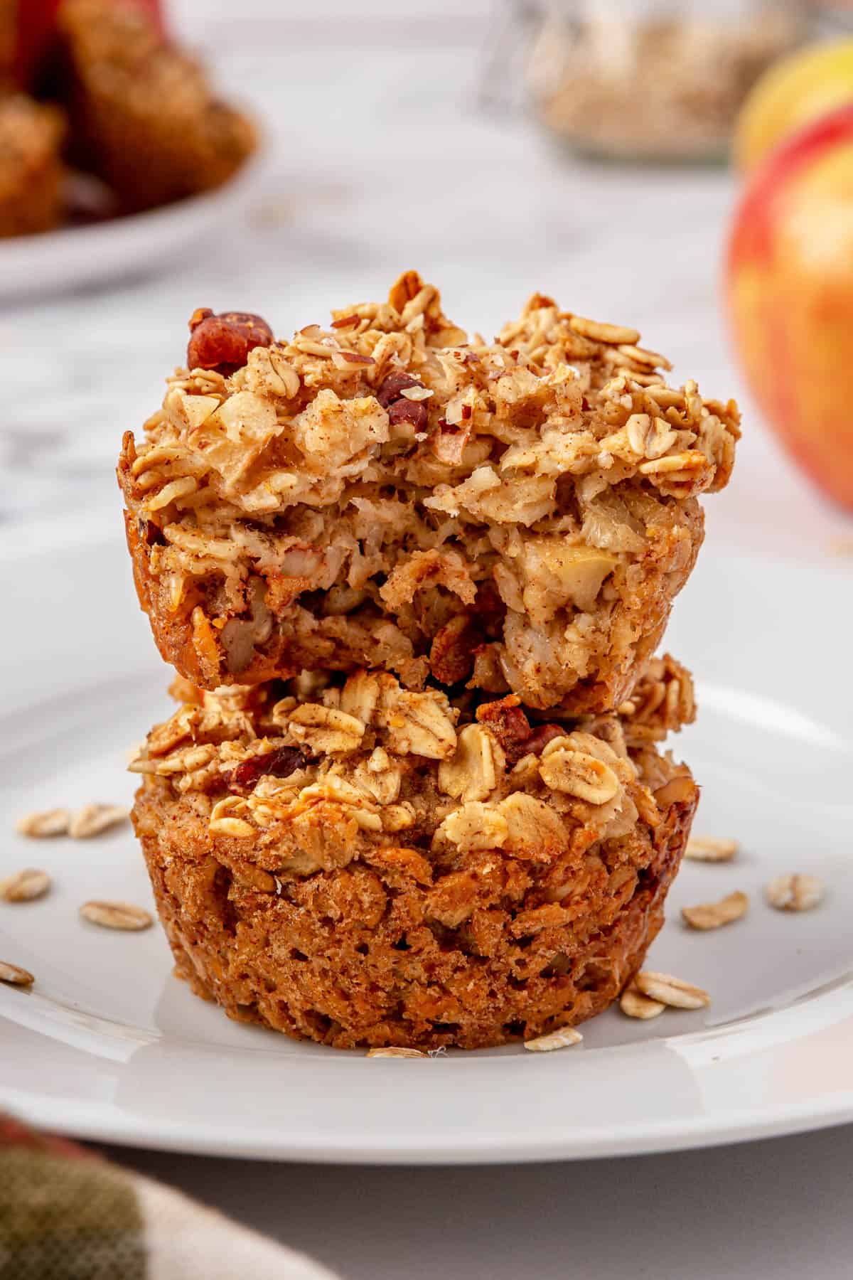 Two apple cinnamon oatmeal cups stacked on a plate with a bite taken out of the top one.