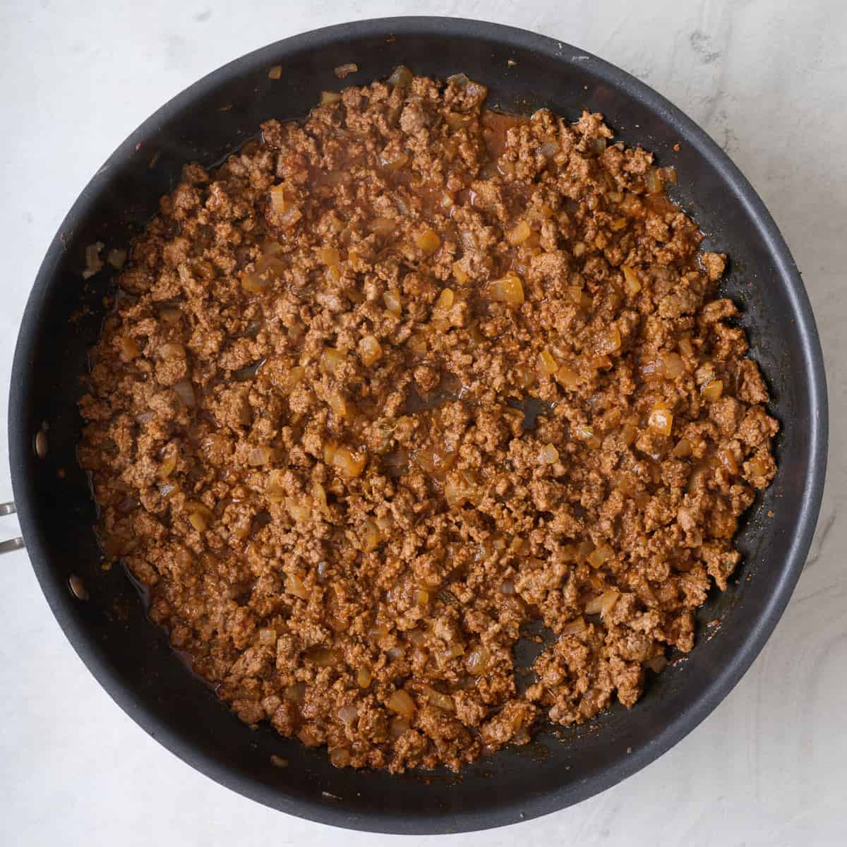 Cooked, spiced ground beef in a skillet.