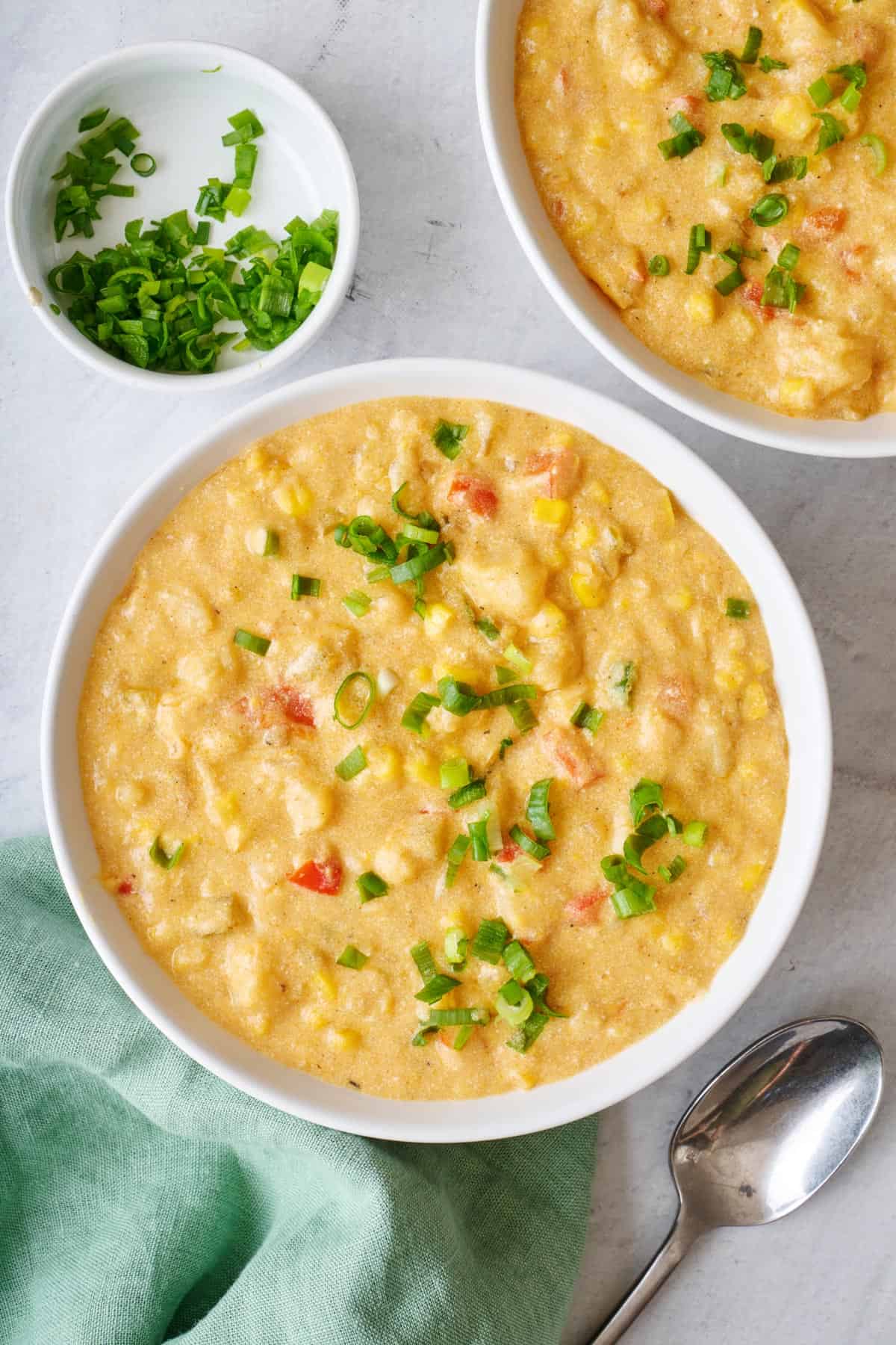 Two bowls of corn chowder topped with green onions.