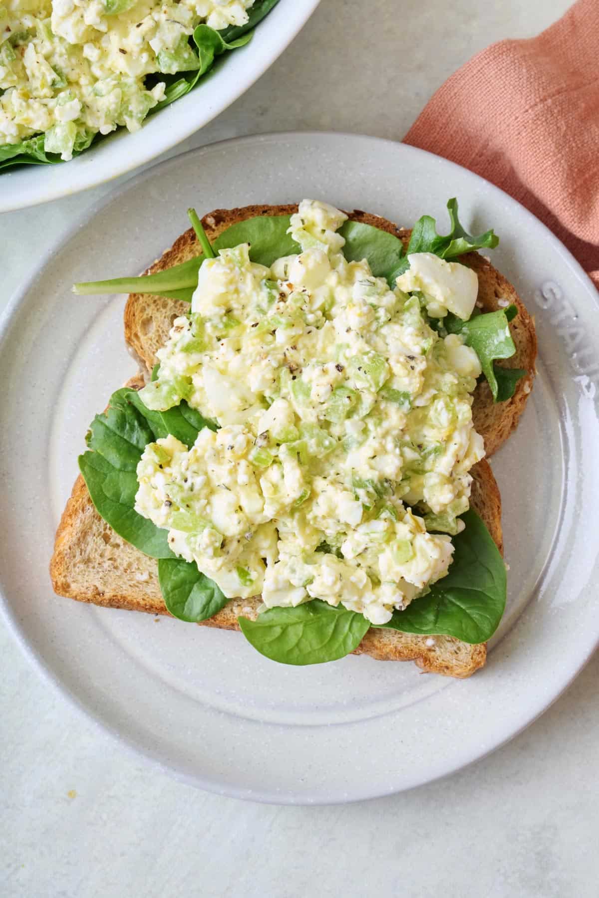 Cottage cheese egg salad on top of slice of bread (open faced sandwich) with mixed greens underneath the egg salad.