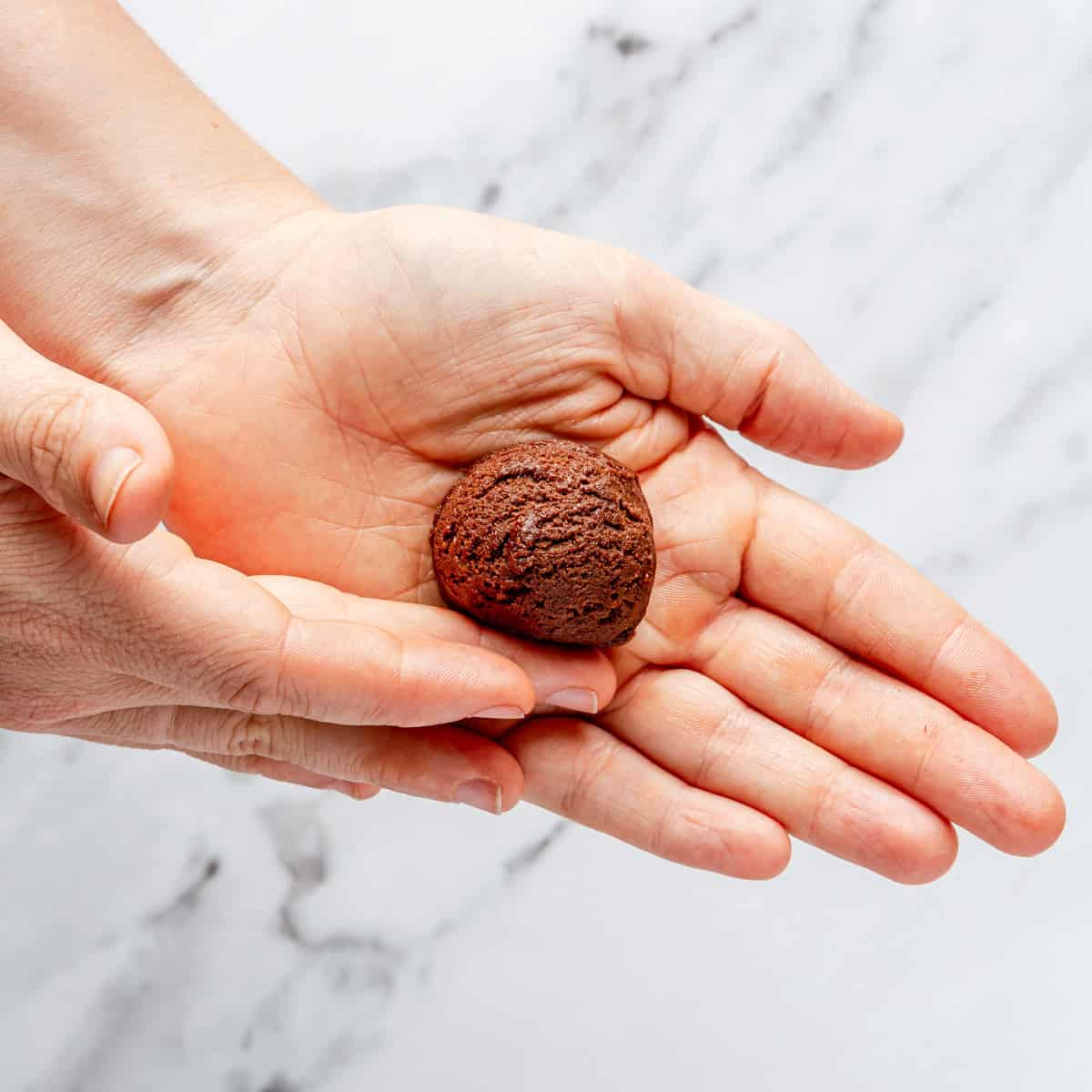 Rolling a cookie dough ball in hands.