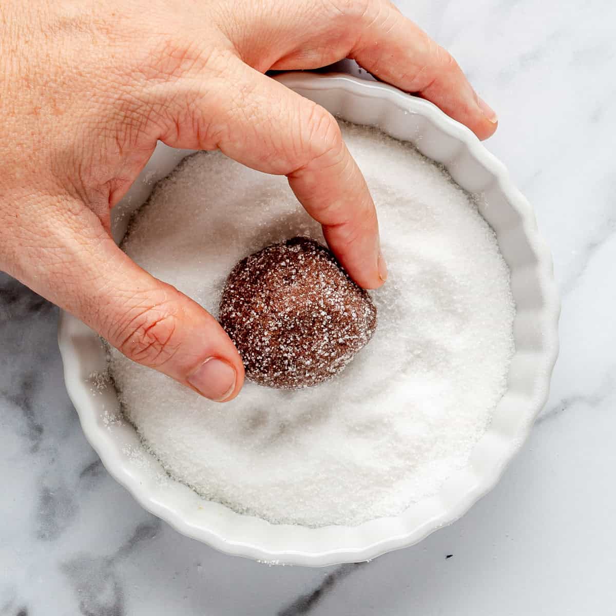 Rolling dough ball into sugar.