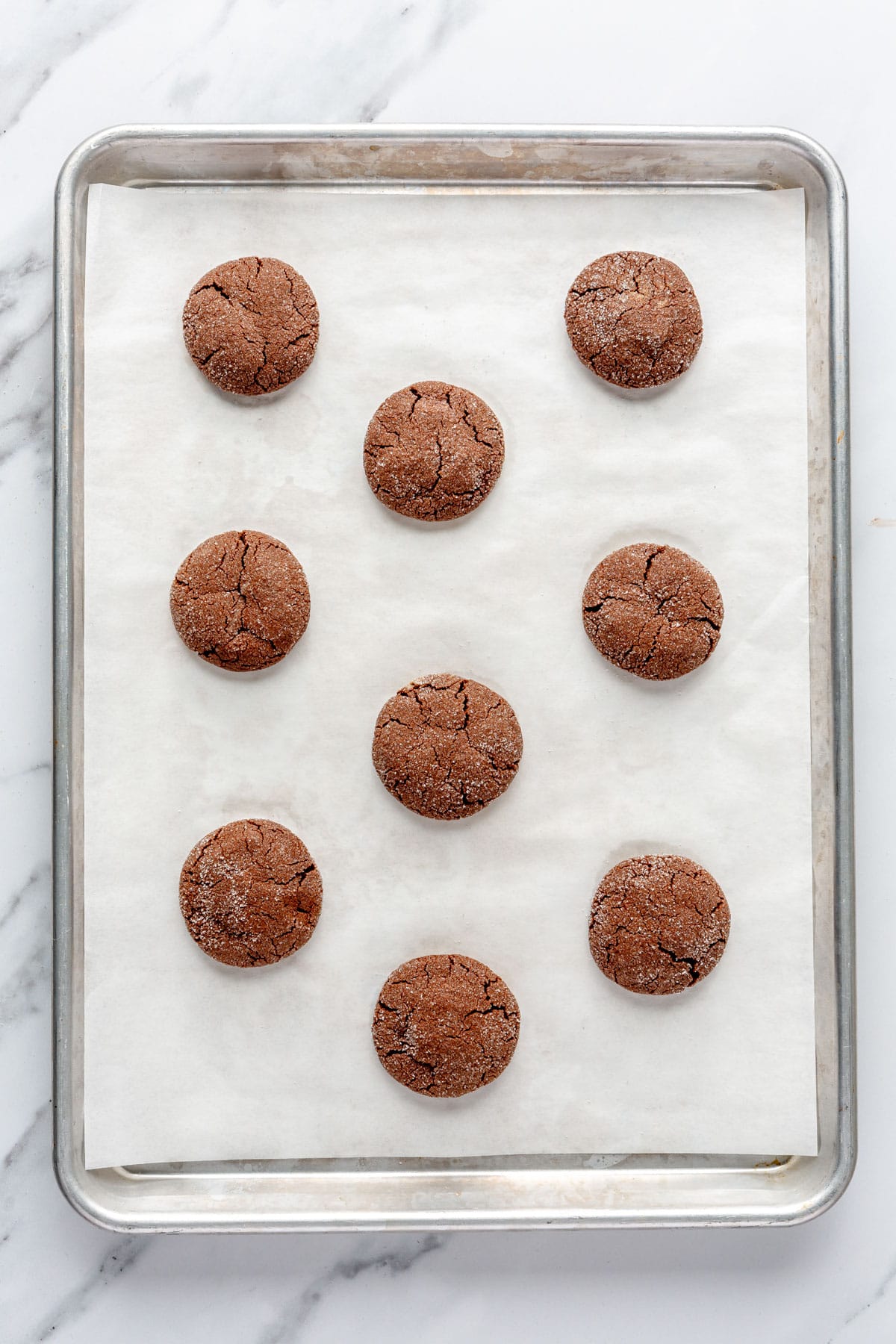 Tray of cookies on a parchment lined baking sheet after baking.