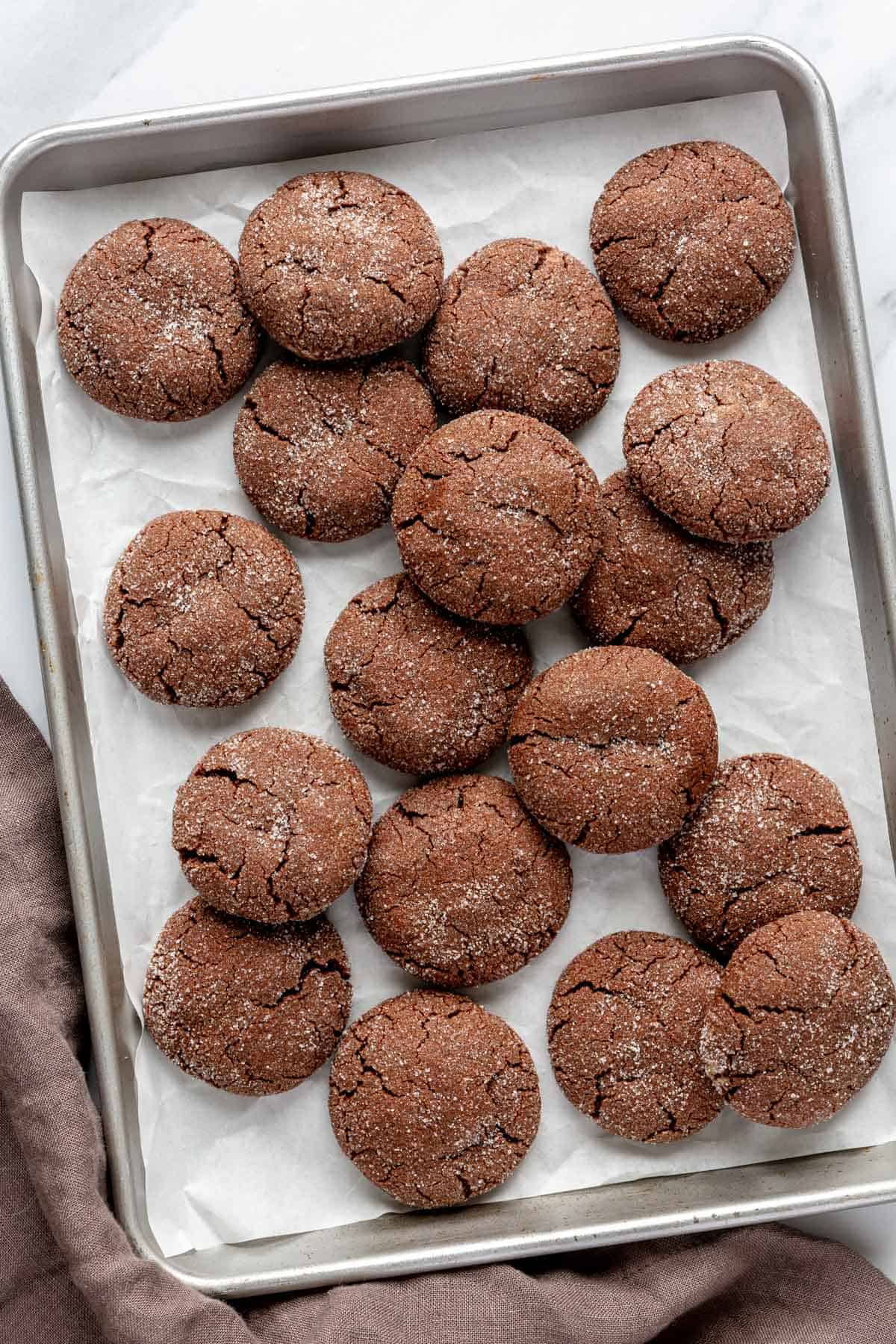 Chocolate sugar cookies layered on a baking sheet.
