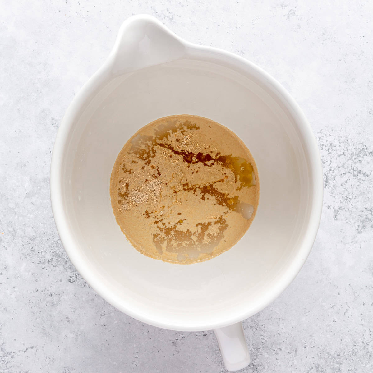 Water, yeast, honey, oil and salt in the bowl of a stand mixe.