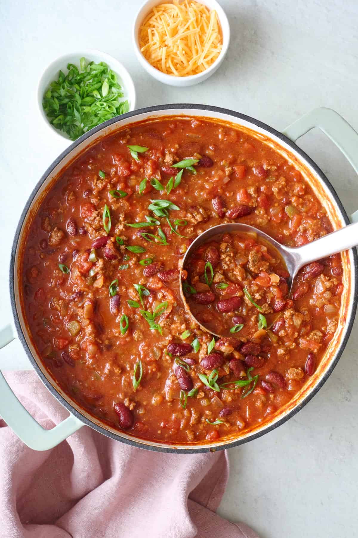 Beef chili in a pot with a ladle dipped inside.