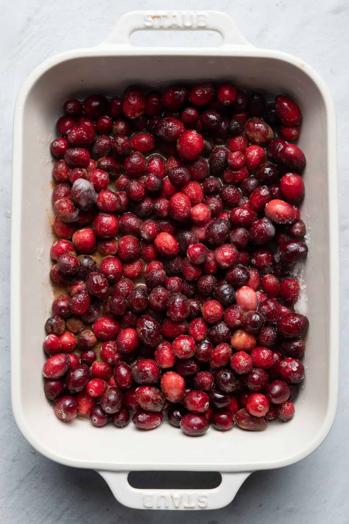 Fresh cranberries in a baking dish with sugar.