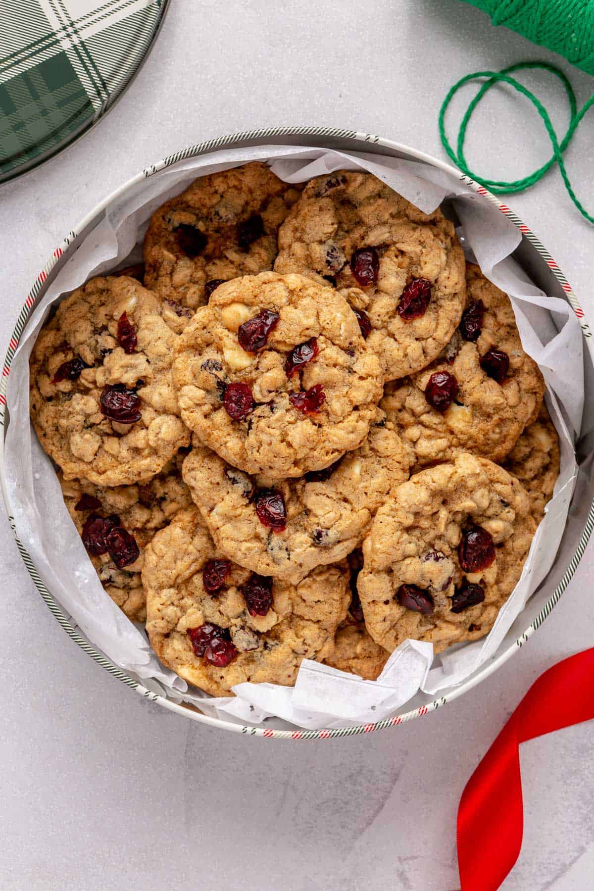 Chewy oatmeal cranberry cookies with white chocolate chips in a holiday tin for gifting.