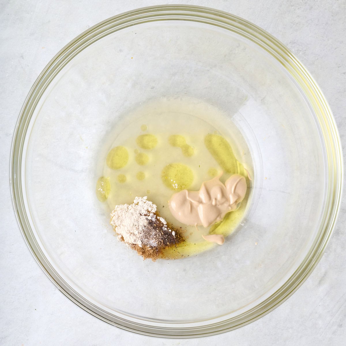 Oil, mustard, lemon juice, and seasonings in a bowl.