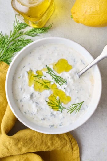 Creamy Greek yogurt dipping sauce in a small bowl garnished with fresh dill and olive oil.