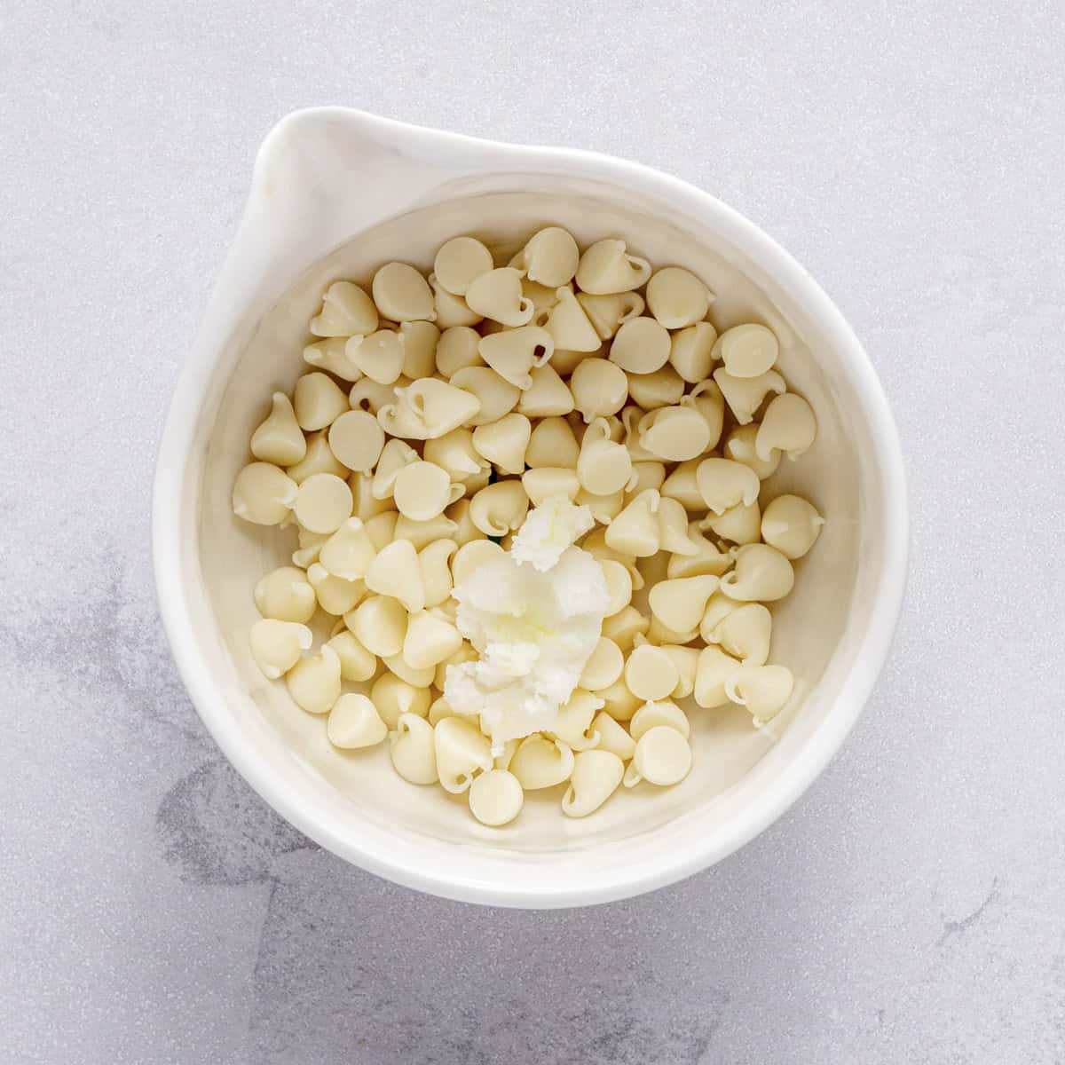 White chocolate chips and coconut oil in a small dish.