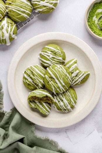 Matcha cookies with white chocolate drizzle on a plate.