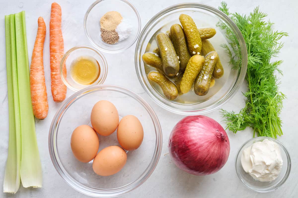 Ingredients for recipe: celery, carrots, spices, oil, boiled eggs, dill pickles, red onion, fresh dill, and yogurt.