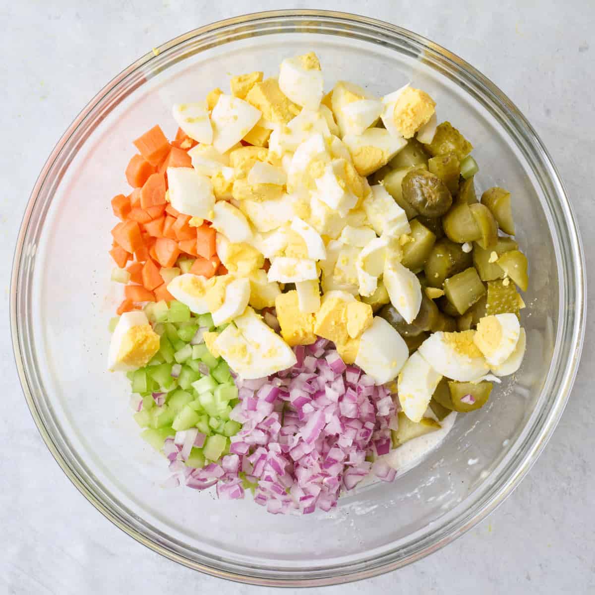 Chopped eggs, carrots, celery. red onion, and pickles on top of salad sauce.