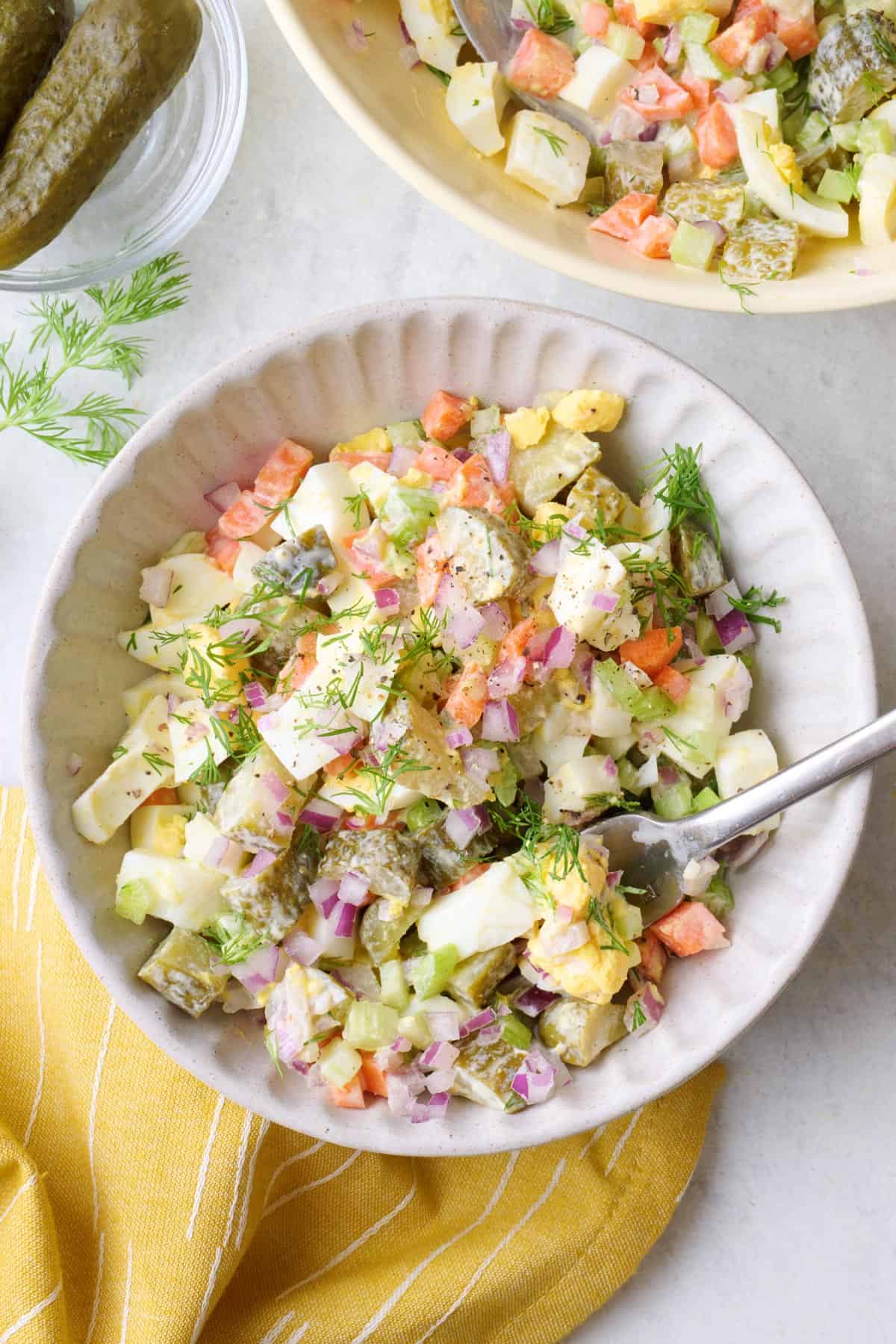 Serving of dill pickle salad in a small bowl with fork dipped inside.