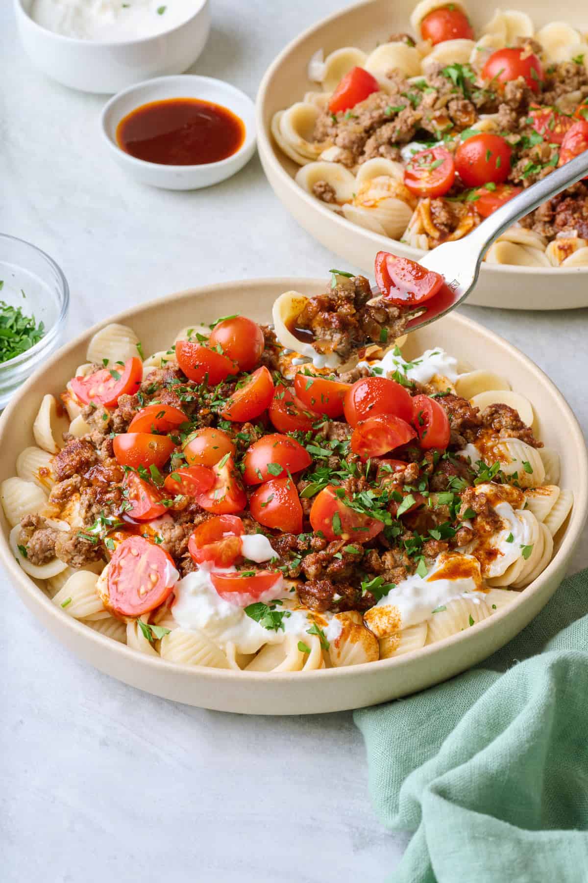 Fork lifting up a bite of Turkish pasta from plate.