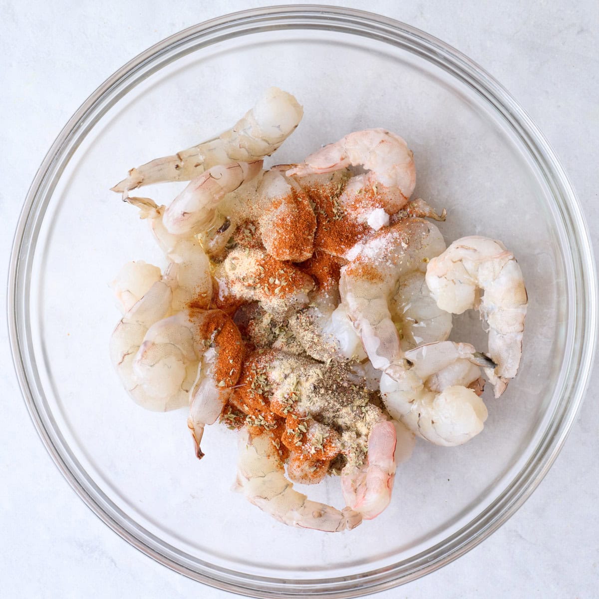 Shrimp, oil and seasoning in a bowl before coating.