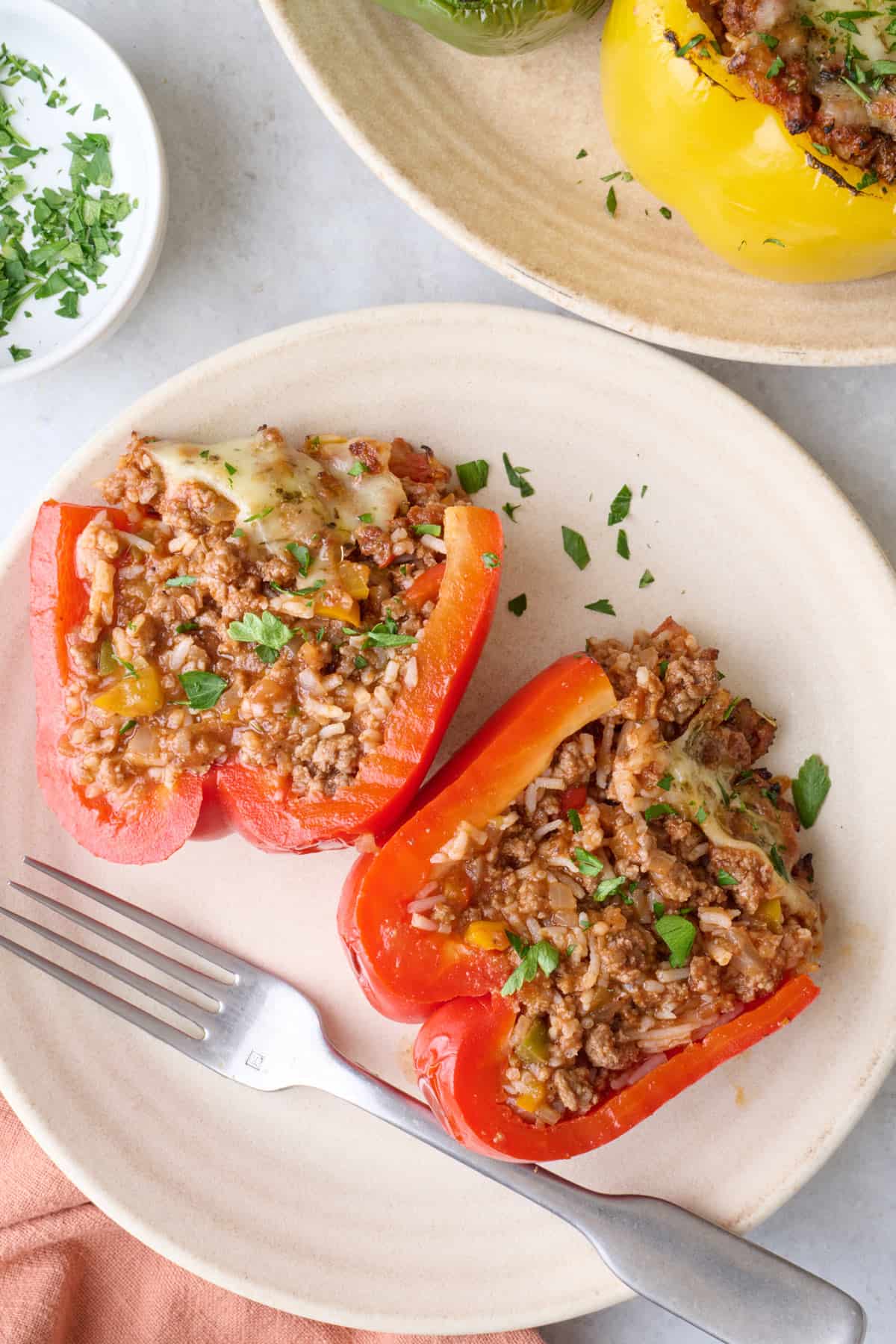 Air fryer stuffed pepper on a small plate cut in half to show filling inside.